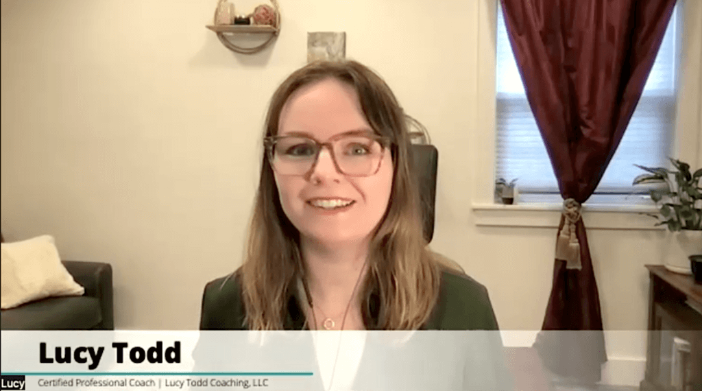 Screenshot of career discovery coach Lucy Todd, CPC, in a video conference. She wears a green button-down shirt and brown translucent glasses and sits in a home office