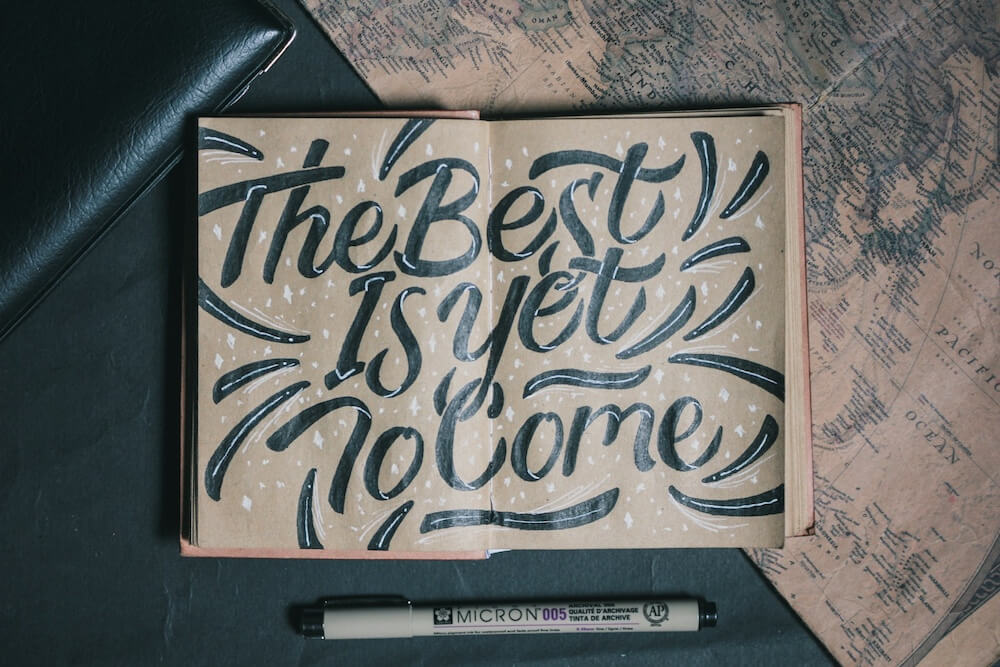 An open notebook with natural brown paper and black-and-white calligraphy reads "The Best Is Yet To Come" — and when it comes to deciding "what is a perfect job for me?", always remember that the best IS yet to come!
