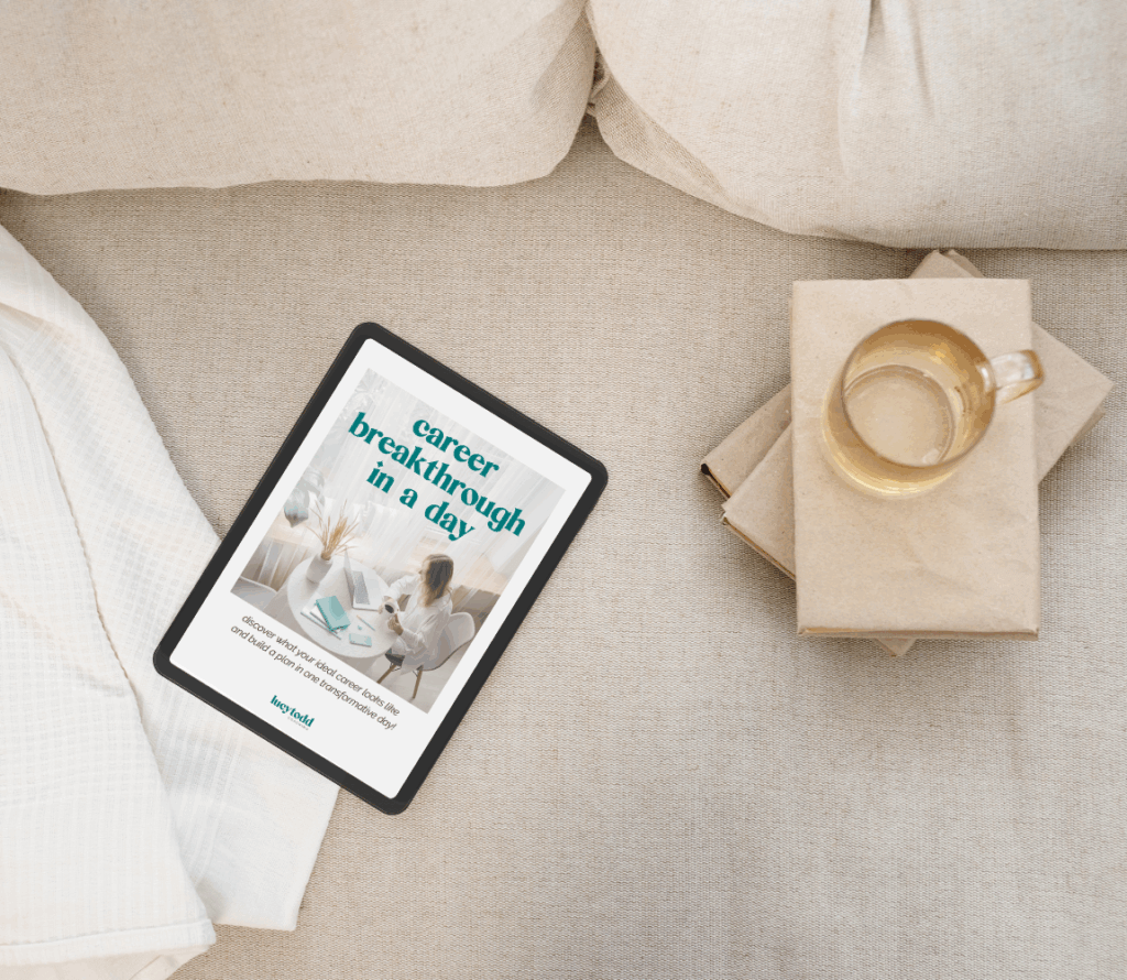 A beige linen couch with white waffle throw blanket, stack of notebooks, and a clear glass mug alongside a black tablet. On the tablet screen is an ebook workbook by Lucy Todd Coaching: Career Breakthrough in a Day, the career offsite planning guide for solo career transition planning