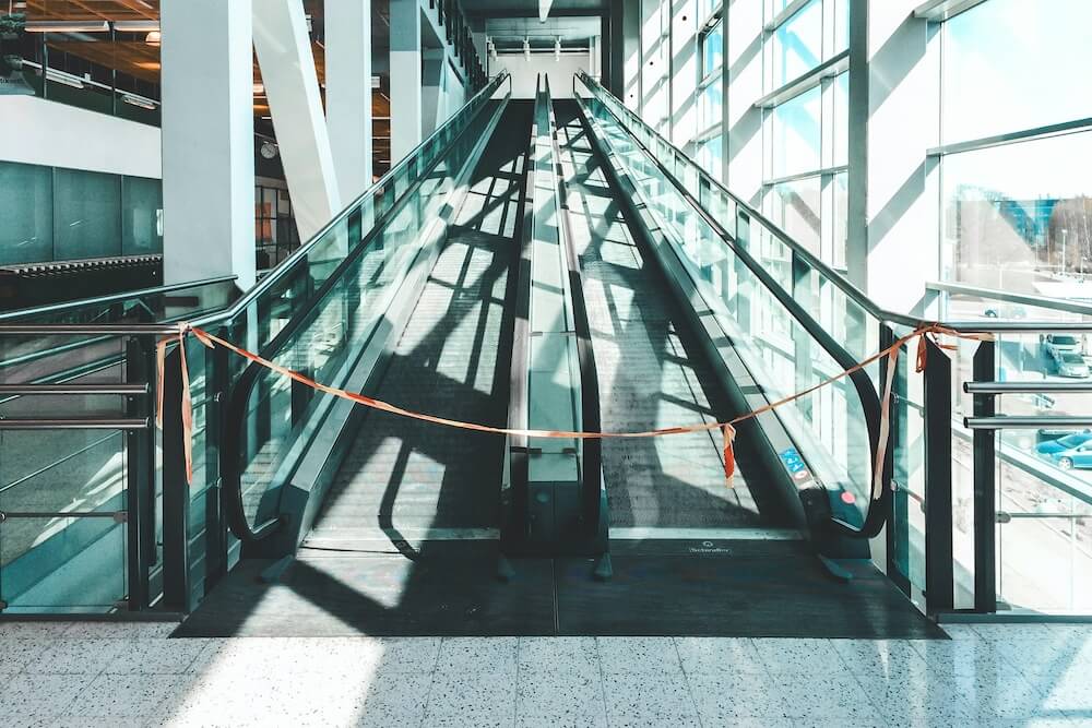 An uphill moving walkway in an empty building, roped off with orange tape as though out of order — representing no room for "upward mobility" or growth in your job